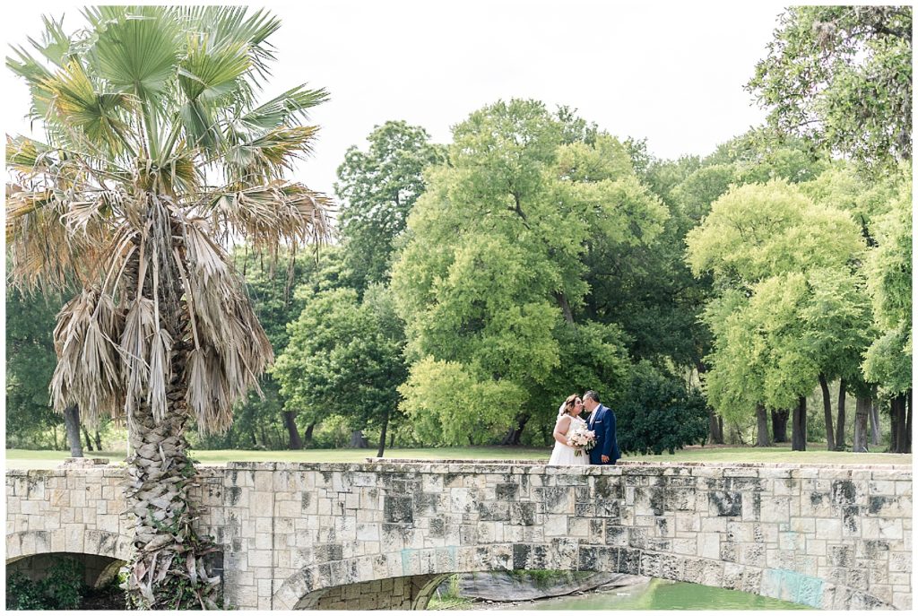 bride and groom standing on a bridge