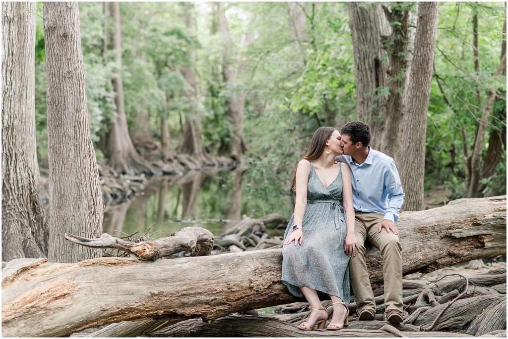 Man and woman sitting on a log kissing at cibolo nature center
