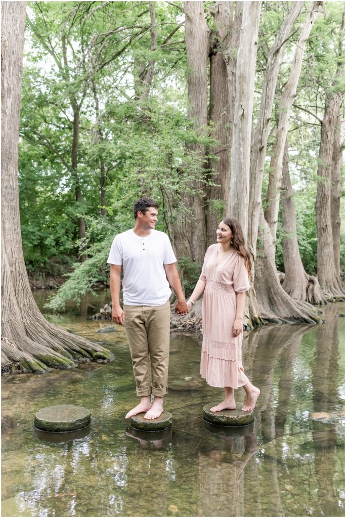 man and woman standing on stumps in a creek at cibolo nature center