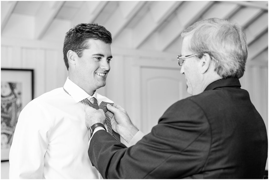 Father of groom helping put tie on